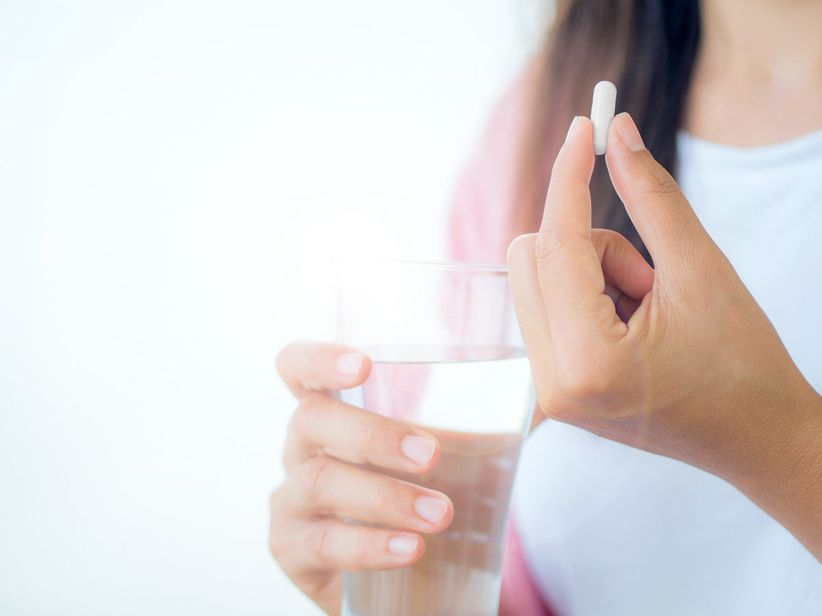 glass of water and pill in hand