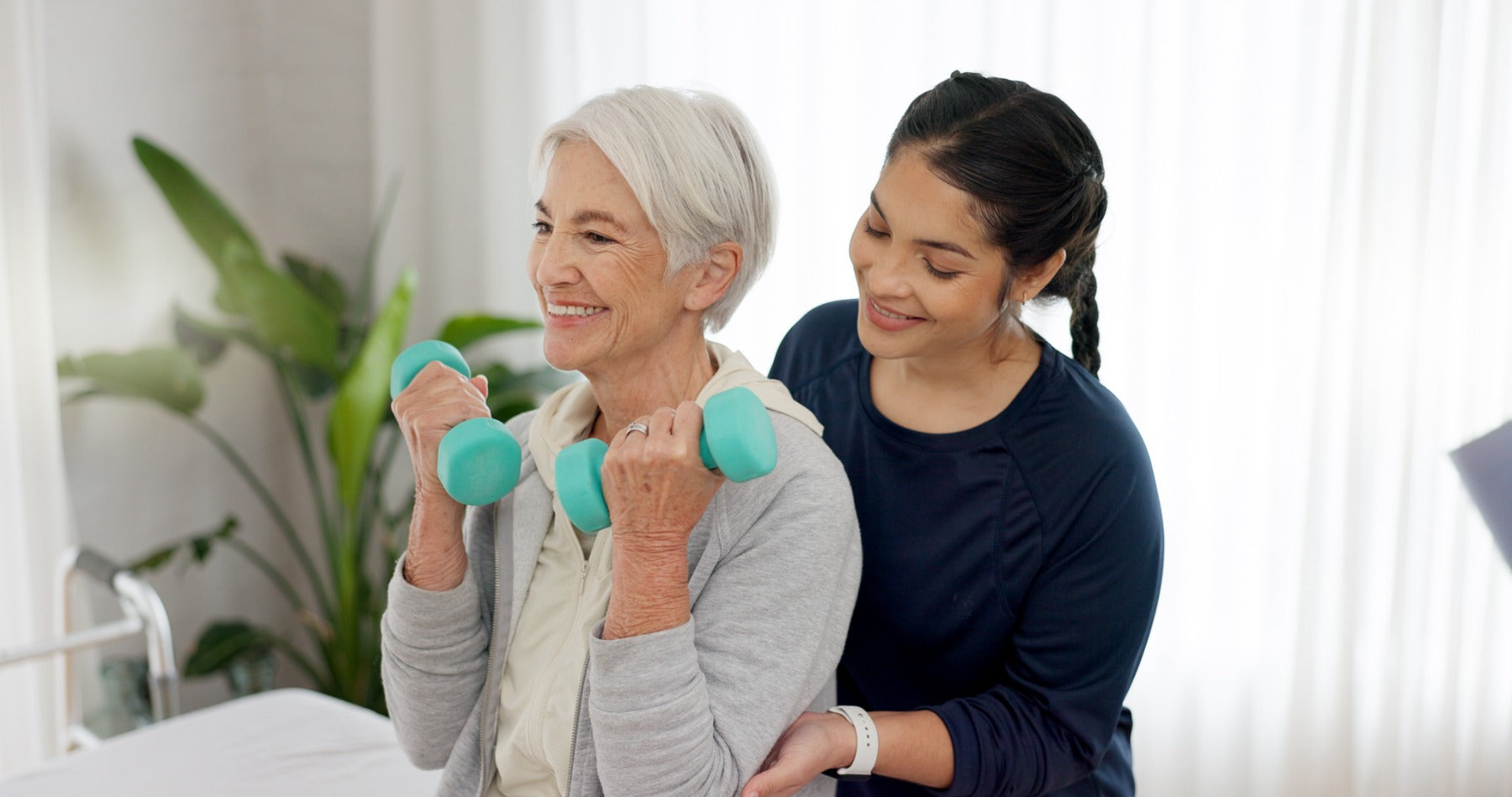 elder lady lifting dumbbells with woman guiding her