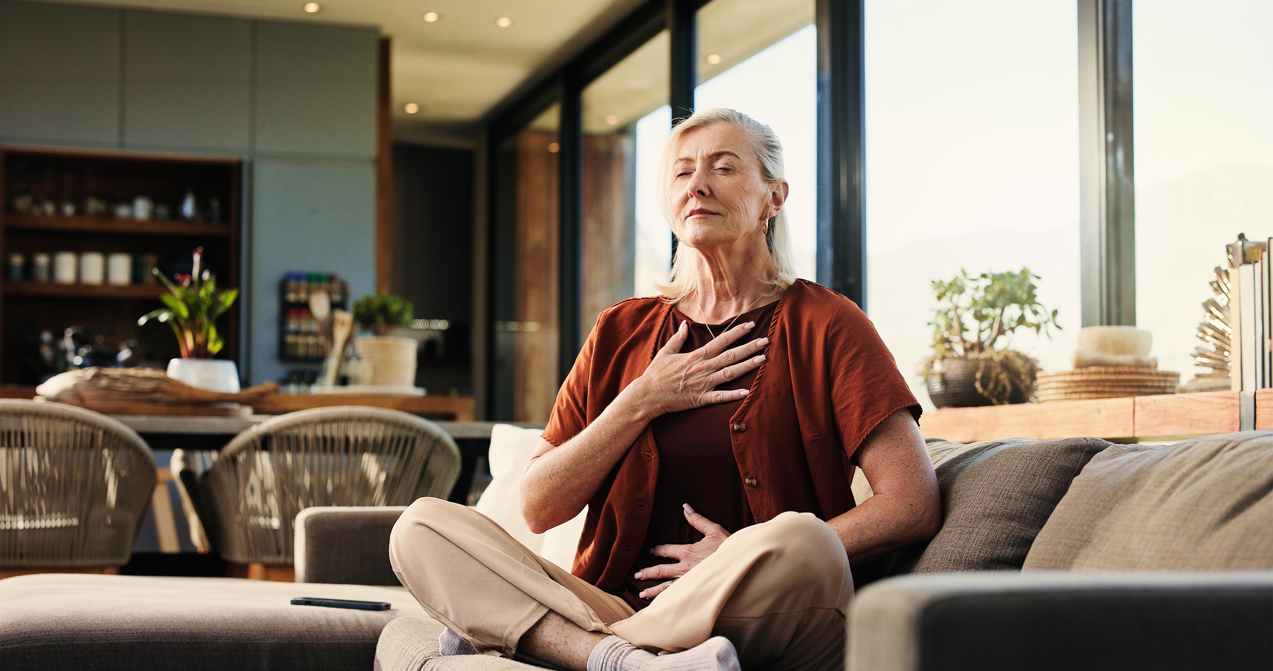 health and senior woman on sofa in home with balance, calm or zen practice in living room.